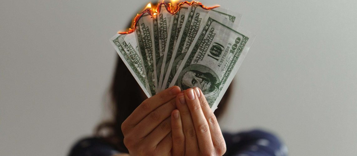 a woman burning money to represent rising print costs
